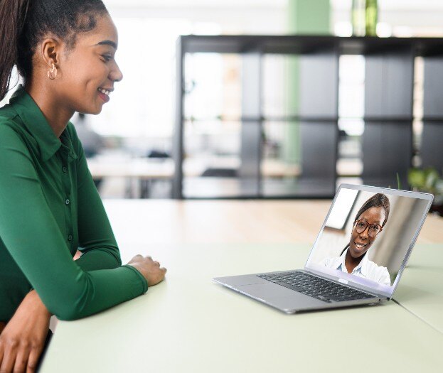 A Black female chatting with a co-worker on a laptop. 